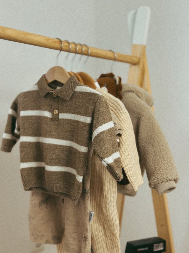 Kindertruien aan hangers op een houten rek